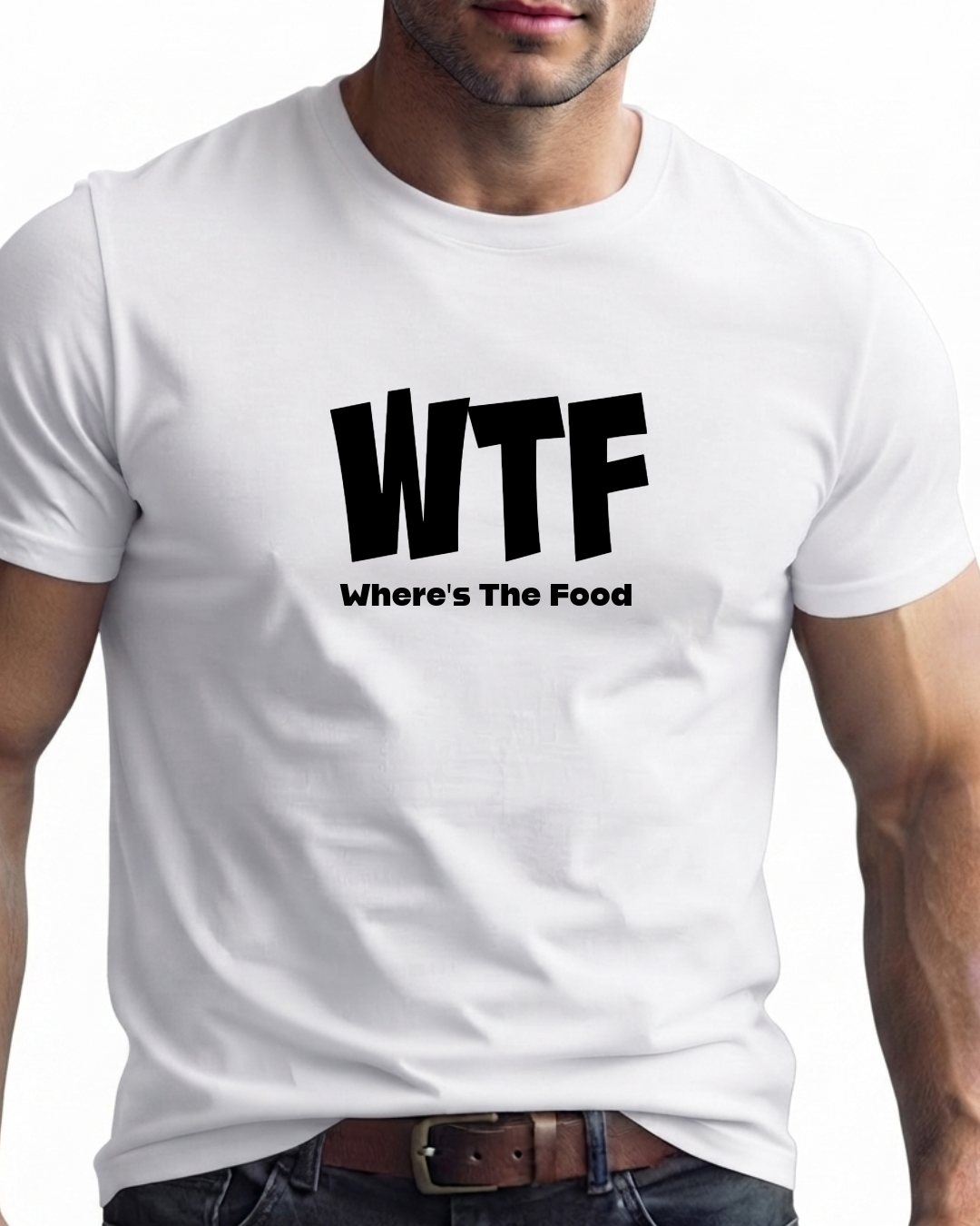 A man wearing a white short-sleeve t-shirt with a bold black graphic print that reads 'WTF' and 'Where's The Food' underneath, paired with dark jeans and a brown belt.